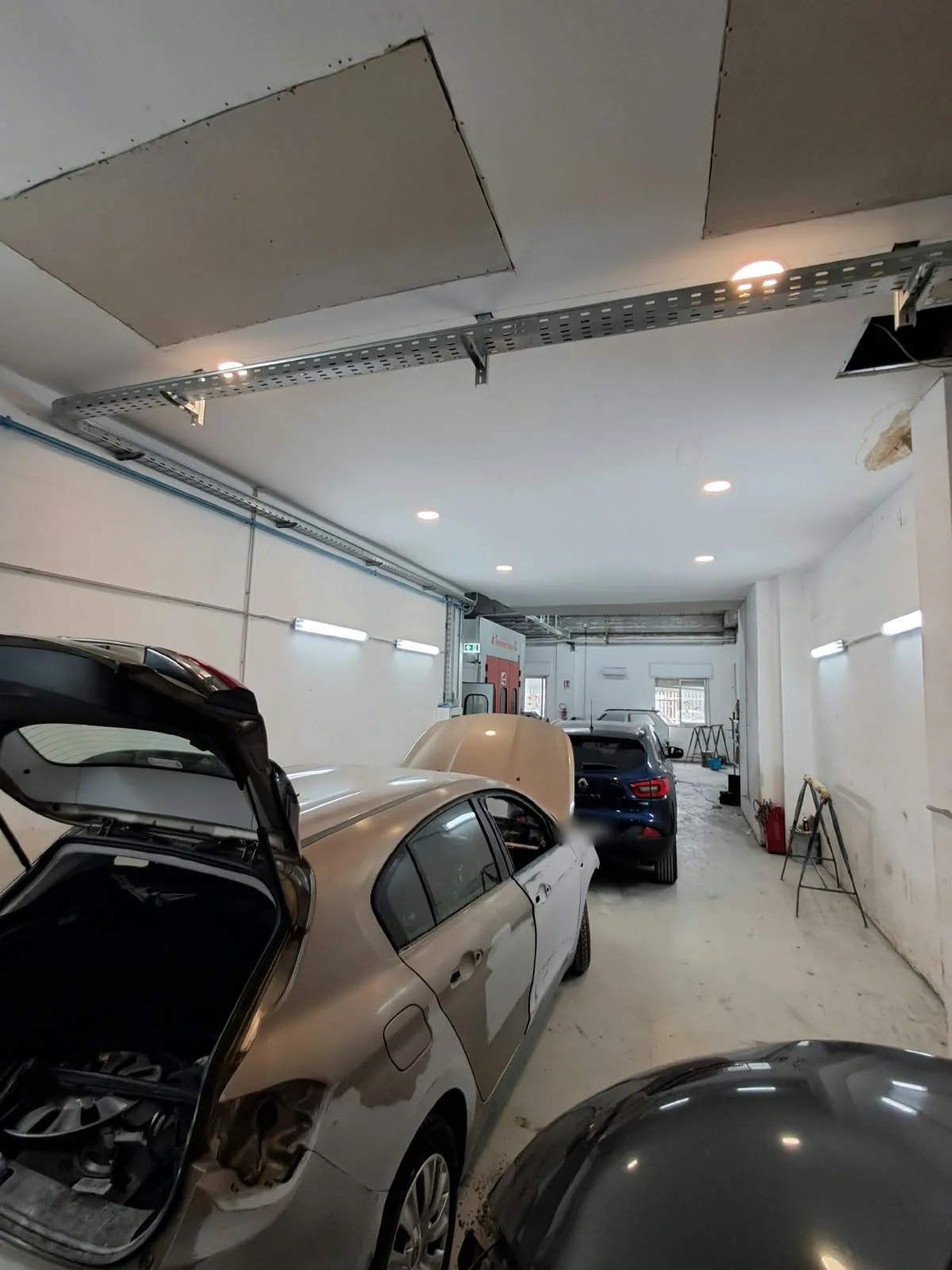 Reparto carrozzeria Giordano RENT con auto in lavorazione e cabina di verniciatura