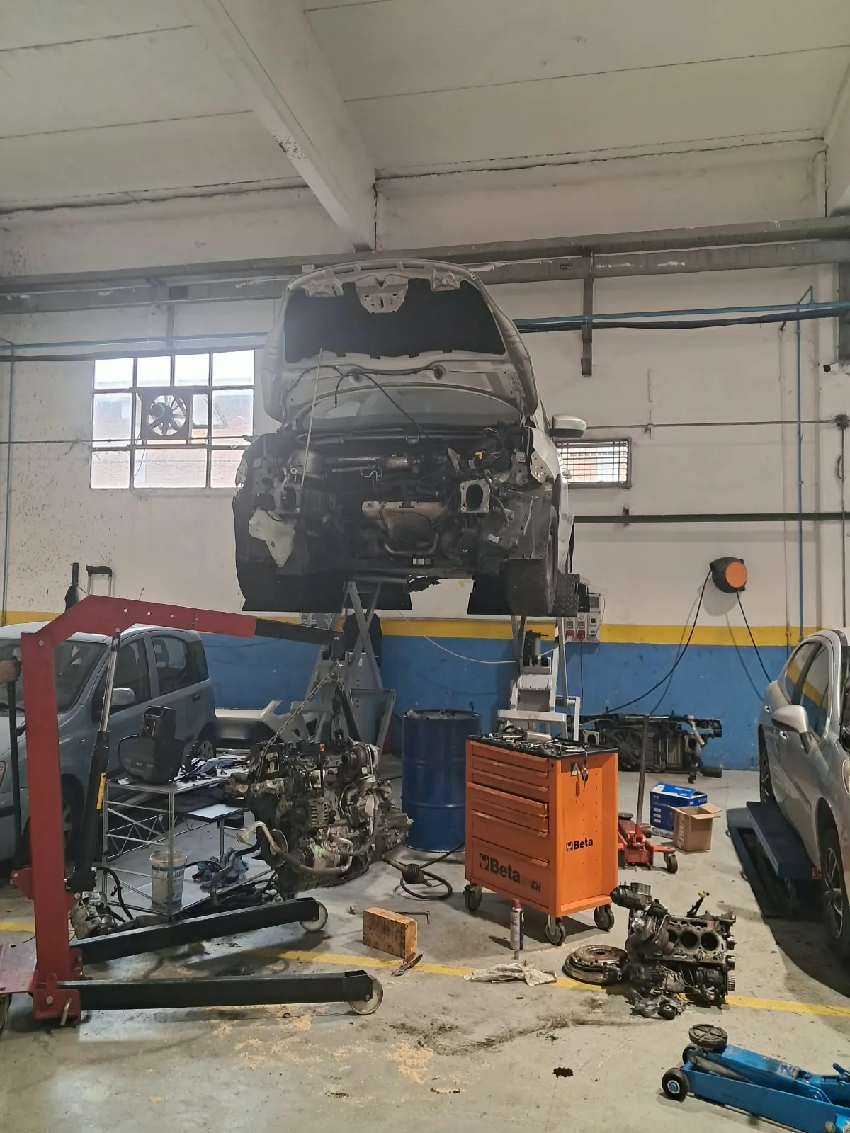 Auto sul ponte sollevatore e motore smontato nell’officina Giordano RENT